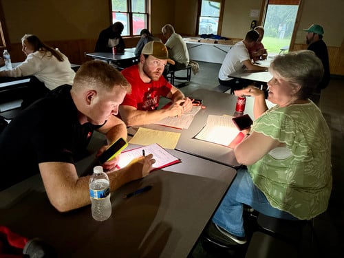 coaches at a table using phones as flashlights