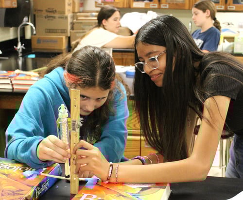 Two girls measuring with ruler in science lab