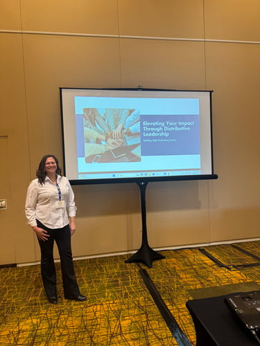 anna beatty standing in front of a projection screen in a conference room