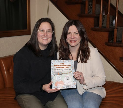 abby brixius and sam deeley-burke sitting holding a copy of the book BiThe Adventures of Big Bertha: The Birthday Camp Out