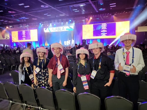 FBLA students at nationals in front of the stage with pink cowboy hats on