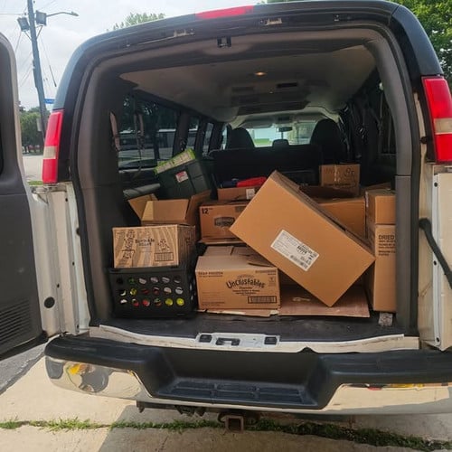 back of a van with the doors open. Inside are boxes full of school supplies