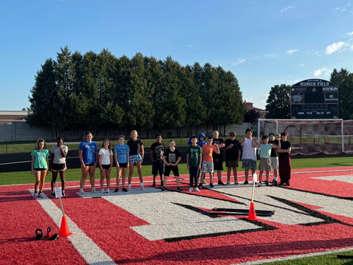 strength and speed students standing on the endzone of the ships football field