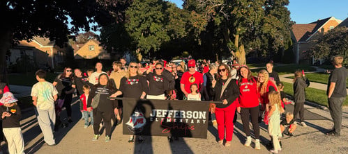 students and staff from jefferson pose during the homecoming parade with their banner