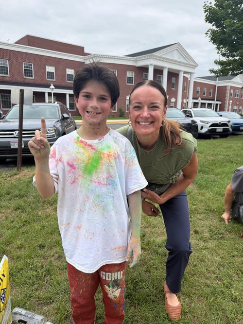 student in white shirt with colorful dye stand with principal