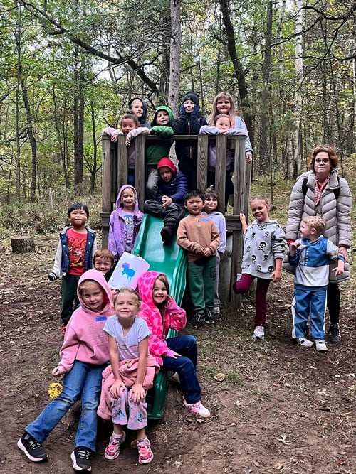 students pose on a slide at the school forest