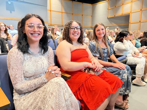 Three Rising Phoenix grads smile in audience