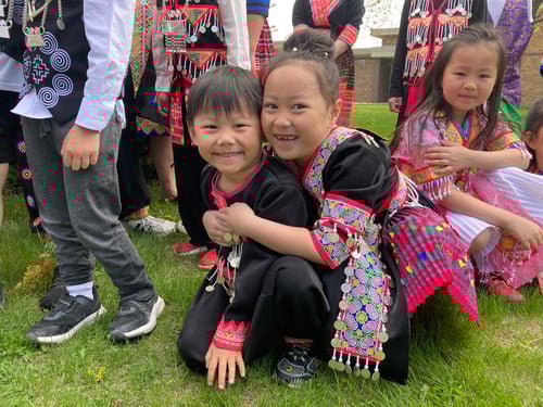 Jackson students in Hmong attire smile and hug