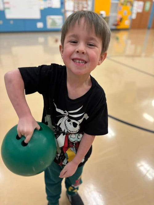 Smiling boy holding up bowling ball