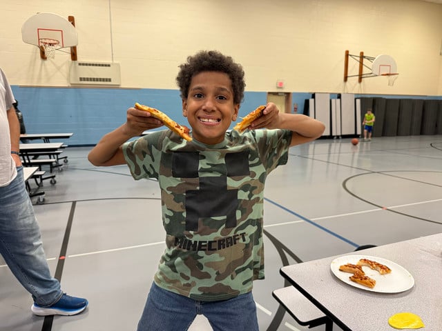 Smiling boy holds slices of pizza