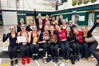 Dance team at competition with plaques